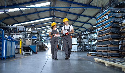 operai-che-camminano-attraverso-un-grande-capannone-di-produzione-e-conversano 1